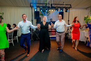Group performing traditional line dance at an indoor celebration with party decorations.