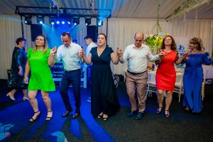 People dancing together at a party with blue stage lighting and festive decorations.