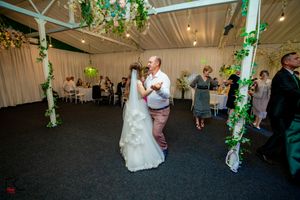 Wedding reception dance with decorative greenery and ambient lighting.