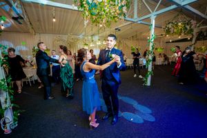 Couples dancing at a wedding reception under green vine decorations and blue mood lighting.