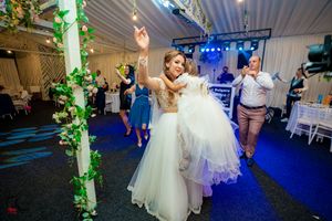 Wedding reception dance floor with blue lighting and green vine decorations on pillars.
