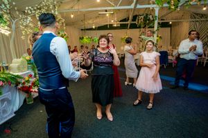 Wedding guests dancing in formal attire at a decorated indoor reception venue.