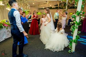 Wedding reception dance floor with guests in formal wear and decorative green accents.
