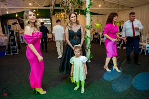 Wedding guests dancing in vibrant outfits under decorative lighting at reception venue.