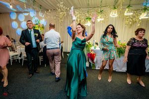 Wedding guests dancing and celebrating under decorative lighting and hanging greenery.
