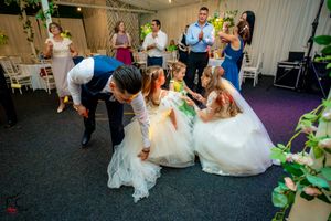 Wedding guests participate in a fun dance game on the reception dance floor with flowing white dresses.