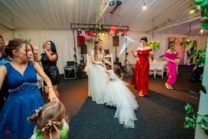 Wedding celebration featuring guests dancing under colorful lighting in a decorated venue.