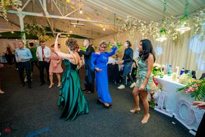 Elegant reception venue with hanging greenery and guests dancing in formal attire.