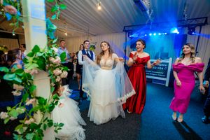 Wedding celebration in full swing with guests dancing under blue and green atmospheric lighting.