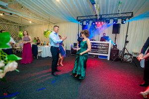 Partygoers dancing and celebrating under colorful stage lighting at an indoor event.