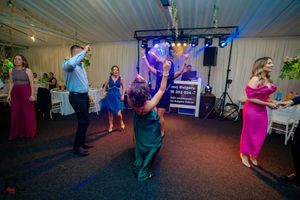 Guests enjoying a lively dance party under blue and purple lighting at an indoor venue.