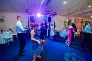 Party guests enjoying themselves under blue lighting at an indoor celebration venue.