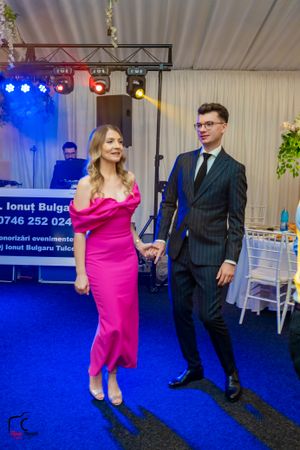 Wedding guests dance and celebrate on a blue-lit dance floor at an indoor reception venue.