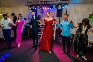 Wedding reception guests dancing together on a colorful dance floor with blue and purple lighting.