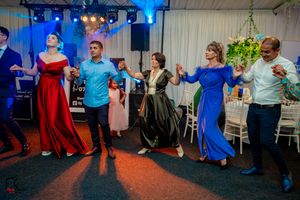 Party guests dancing energetically at an indoor event with dramatic blue lighting effects.