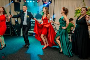 Formal event with people dancing in elegant dresses under stage lighting.