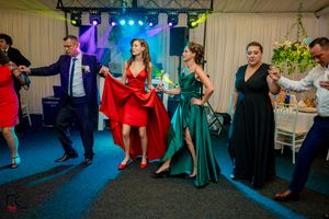 Wedding reception dance floor with guests enjoying themselves under colorful lighting.