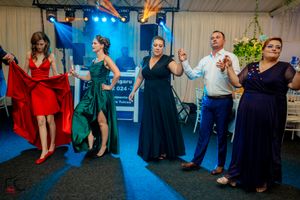 Group of people dancing and celebrating at an indoor event with theatrical lighting.