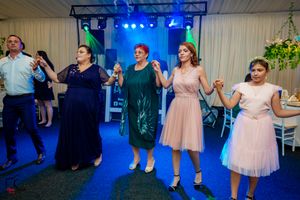 Wedding reception guests dancing together under blue lighting in an indoor venue.