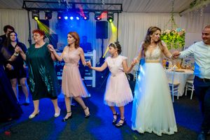 Party guests dancing in formal attire under dramatic blue lighting at an indoor celebration.