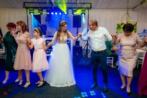 Large group dancing together at wedding reception with professional lighting setup.