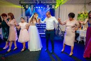Wedding party dancing on illuminated dance floor with festive atmosphere.