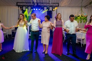 Wedding celebration with guests dancing under colorful lighting effects.