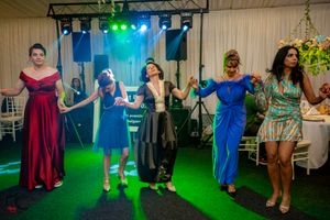 Wedding party dancing and celebrating on illuminated dance floor with dramatic lighting effects.