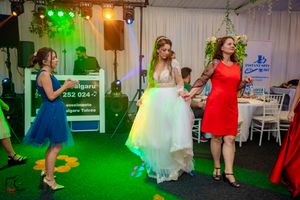 Wedding celebration with guests dancing under vibrant green lighting in a decorated tent venue.
