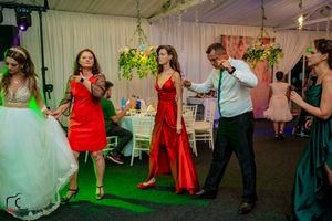 Guests dancing together at a wedding reception under dramatic green and blue lighting.