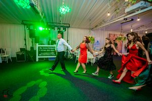 Dance floor scene at wedding reception with green lighting effects and white tent walls.