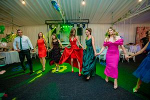 Wedding party dancing in colorful dresses during an energetic group dance routine.