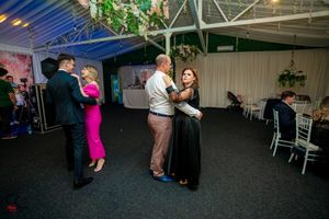 People dancing together in a spacious venue with decorative ceiling trusses and mood lighting.