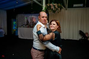 Couples enjoying slow dances at an evening social gathering with mood lighting.