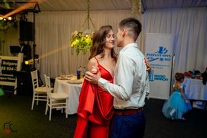 A couple dancing at an indoor event with a woman in a striking red dress.