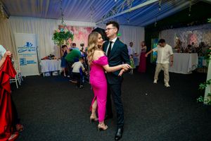 Couples dancing together at an indoor event venue with white drapes and decorative lighting.