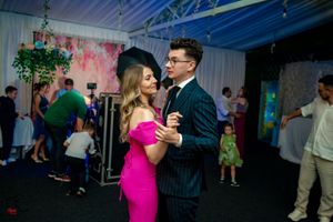 Couples dancing at an indoor event with decorative lighting and hanging plants.