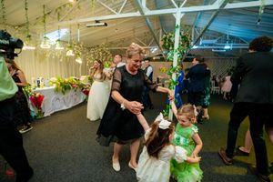 Wedding guests dancing and celebrating in a decorated indoor venue with green accents.