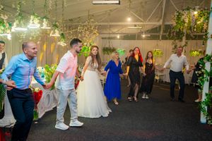 Wedding venue decorated with hanging greenery and string lights as guests celebrate on the dance floor.