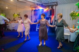 Wedding reception venue with guests dancing under dramatic blue lighting and white ceiling decor.