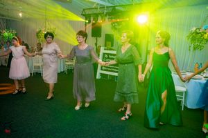 Party guests dancing on a dance floor bathed in bright green and yellow lighting at an indoor venue.