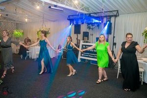 Event space with dance floor and white chairs illuminated by vibrant blue and green spotlights.