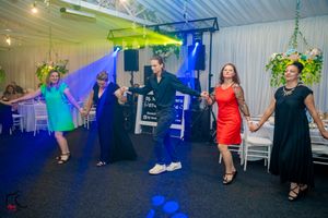 Wedding reception dance floor filled with guests dancing under colorful blue and green lighting effects.