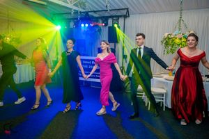 Wedding celebration featuring guests performing synchronized dance moves under colorful lighting effects.