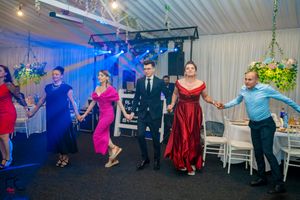Wedding reception guests dancing in a choreographed line formation under multicolored lights.