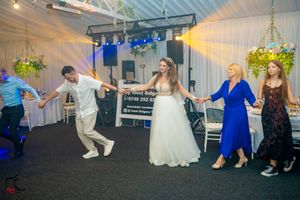 Wedding guests performing synchronized dance moves in a line formation at an indoor venue.