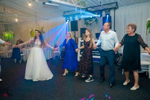 Wedding celebration with dancers forming a circle on the dance floor under blue lighting.
