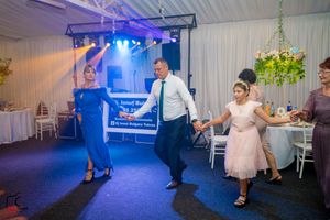Wedding guests dancing together on a colorfully lit dance floor at an indoor reception venue.