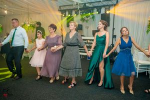 Wedding reception with guests dancing in formal attire under elegant tent lighting.