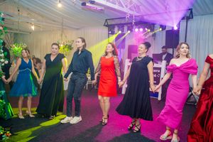 Wedding guests dancing under colorful purple and pink lighting in a decorated venue.